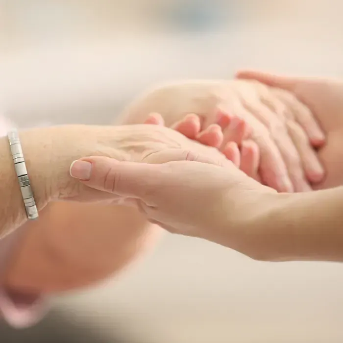 Pflegekraft hält die Hände einer Seniorin in ihren Händen, sinnbildlich für Halt und Unterstützung durch MonCare Alltagsbegleitung
